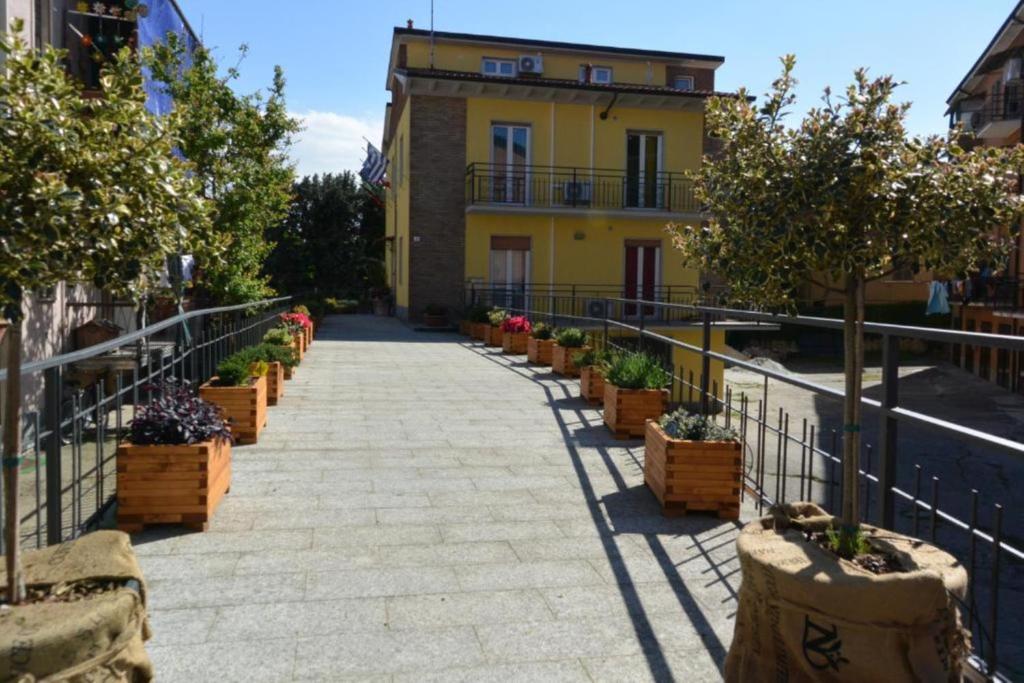 a walkway leading to a yellow building with potted plants at Pavia Ostello in Pavia