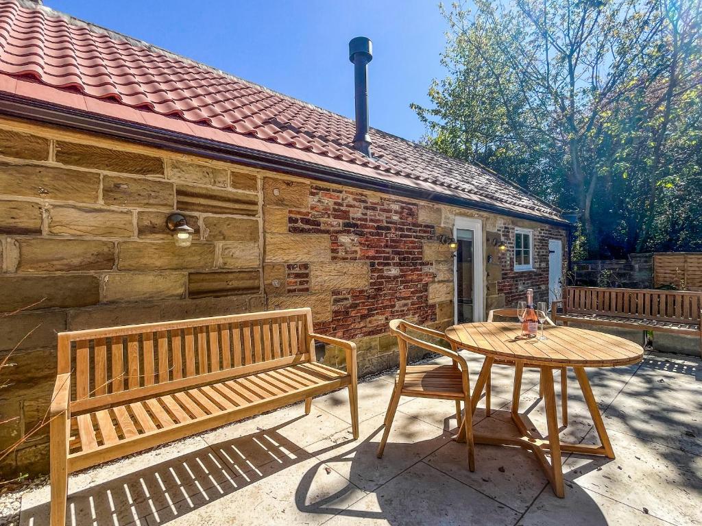 a wooden bench and a table in front of a brick building at Gardeners Cottage - Uk51831 in Great Ayton