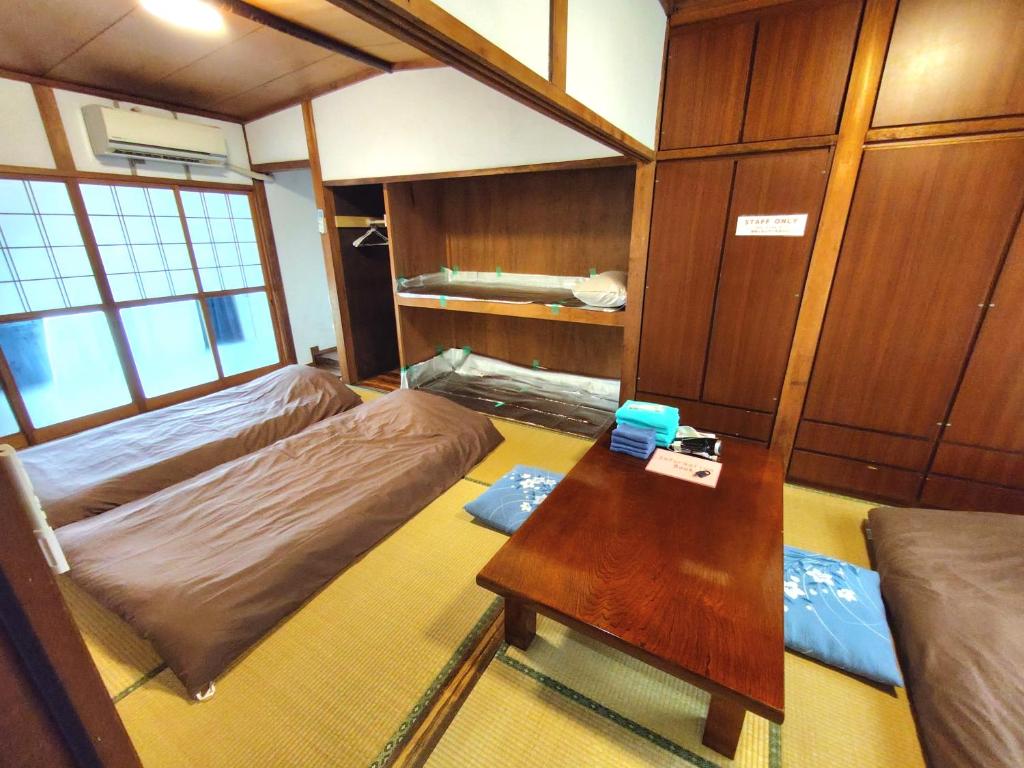 a small room with two beds and a table at OZigaoka Guest House in Otsu