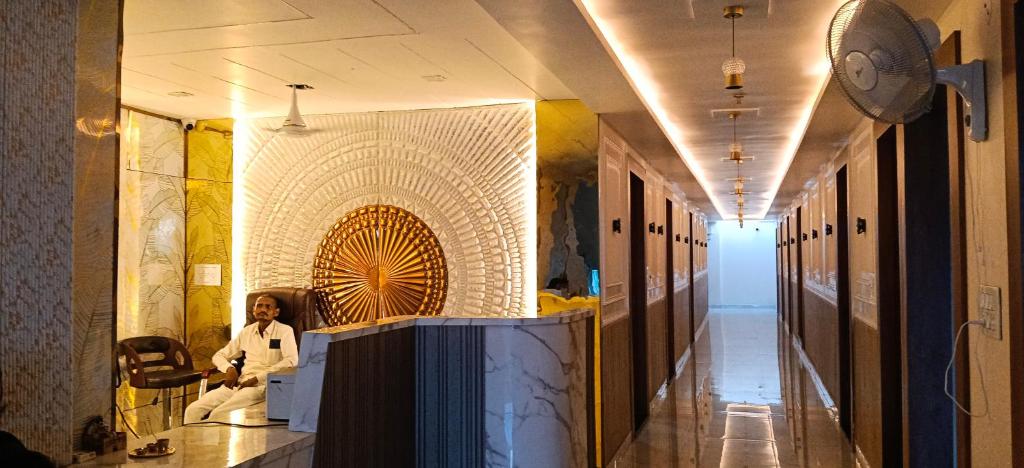 a hallway of a building with a woman sitting on a table at Hotel rajveer in Jhānsi