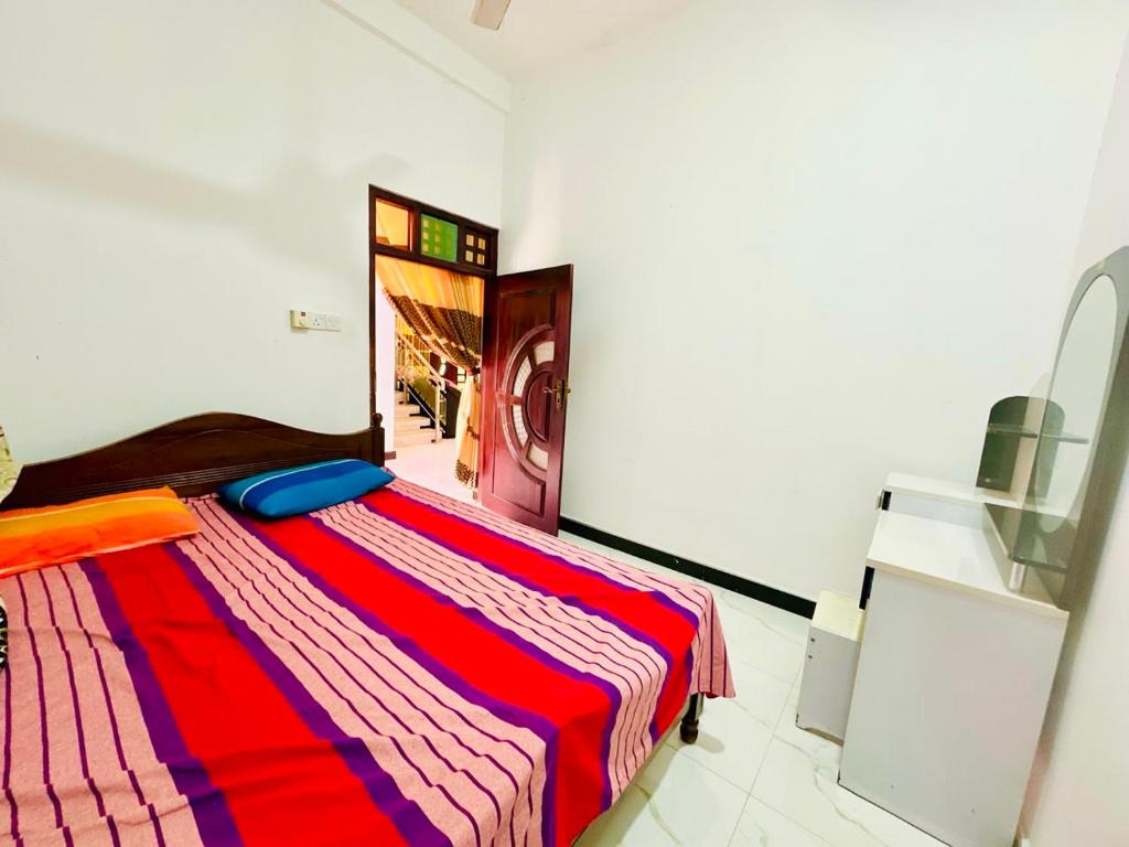 a bedroom with a bed with a colorful striped blanket at Cleopatra villa in Kattankudi