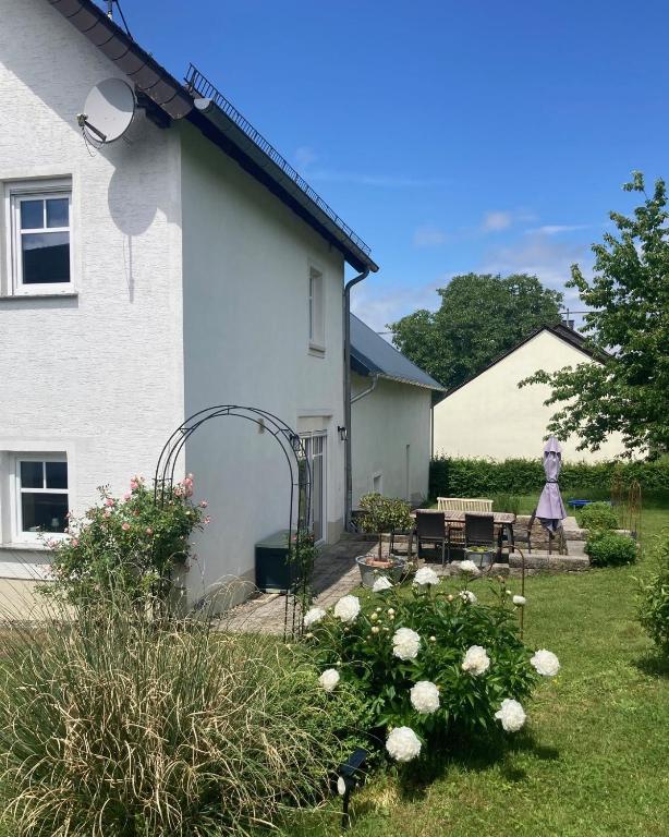 a yard with a white house with a table and flowers at Landhaus Laux in Schmitt