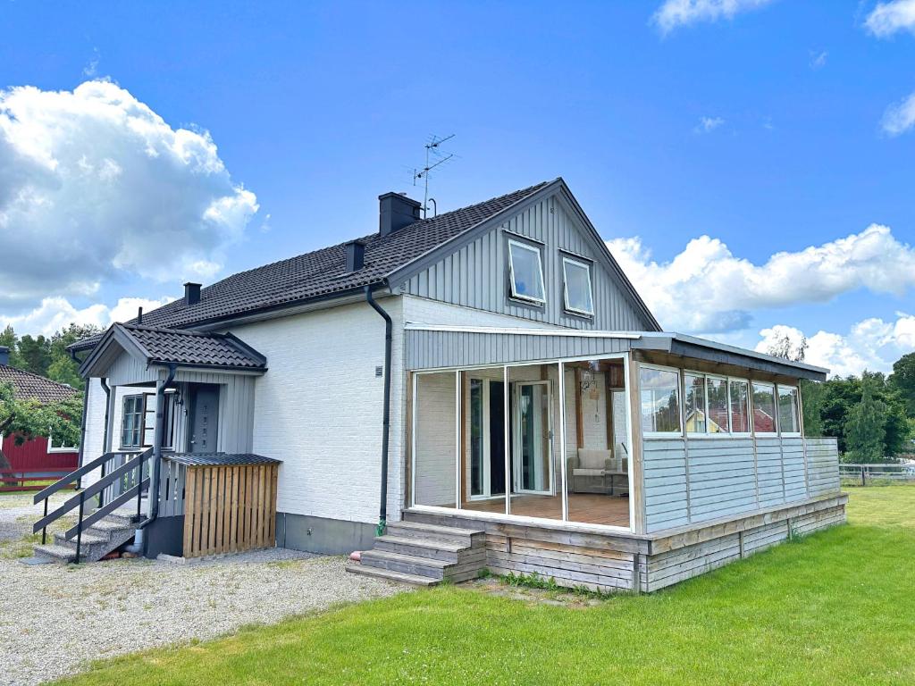 a small white house with a porch on a lawn at Villa Dångebo in Tingsryd