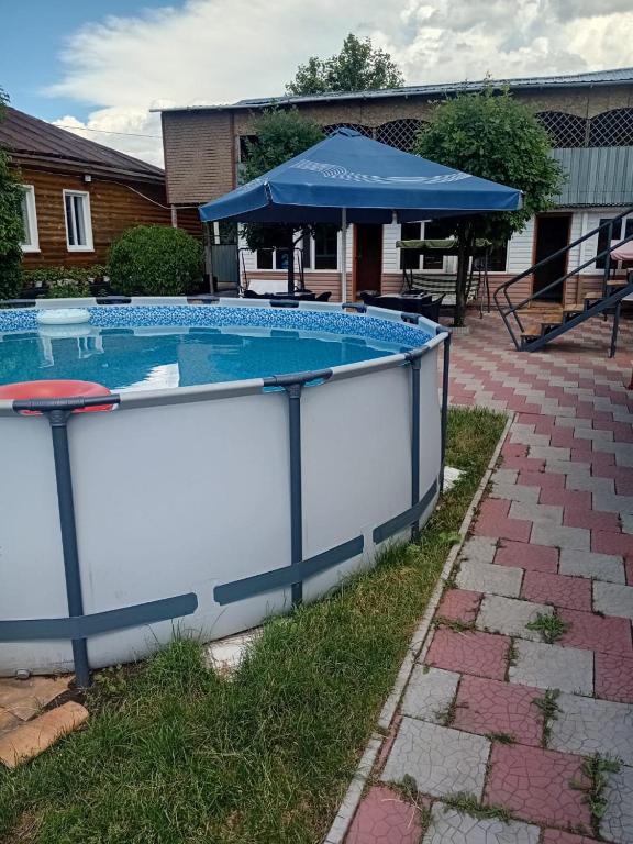a large swimming pool with a blue umbrella at Comfort Guest House in Borovoye