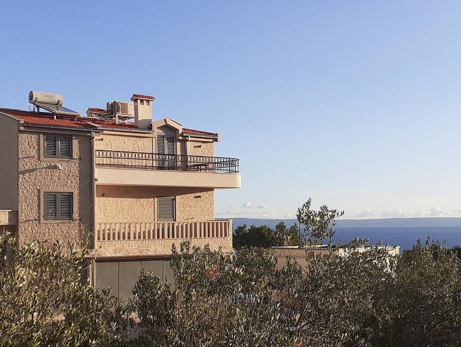 a building with a balcony and the ocean in the background at Stone House Bonaca with Sea View in Baška Voda