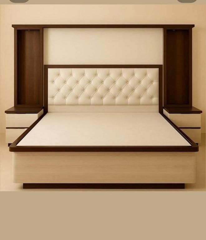 a bed frame with a white mattress and wooden shelves at URWURI Motel in Butare
