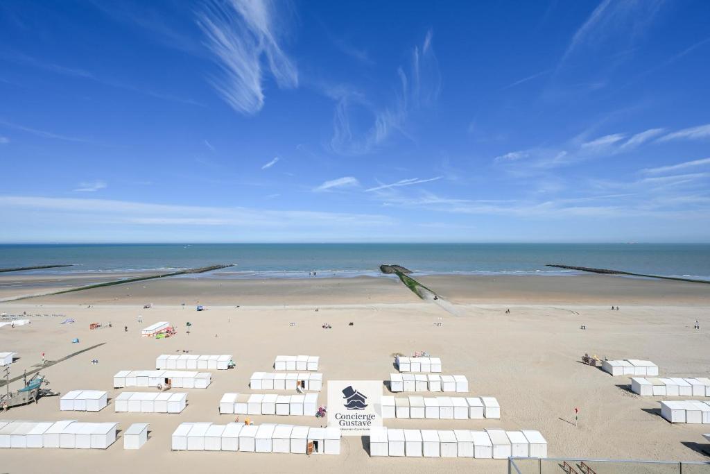 a beach with white umbrellas and people on the beach at Drakkar in Wenduine