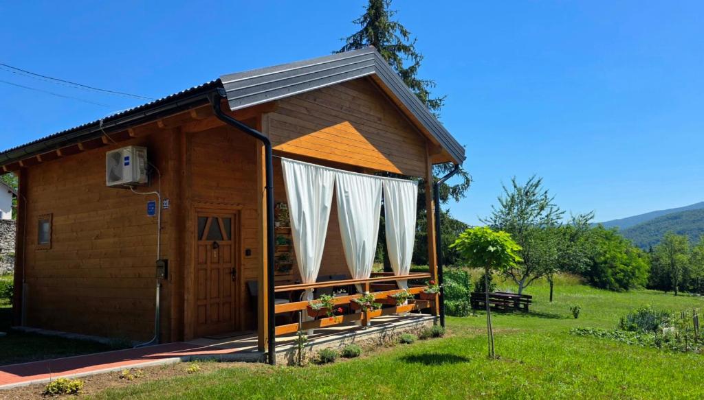 a small wooden cabin with a door and curtains at Lorraine's cabin Plitvice in Drežnik Grad