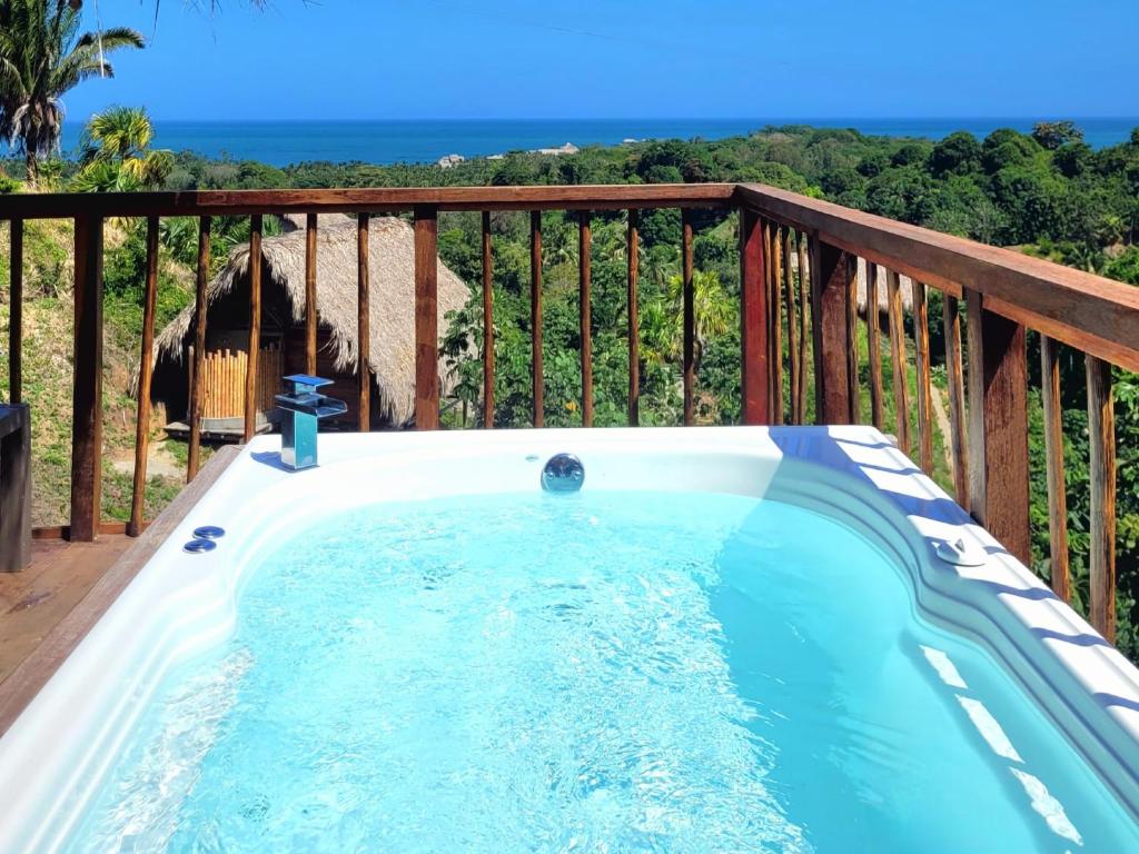 a hot tub on a deck with a view of the ocean at Cabaña Guacamaya Vista al Mar y Jacuzzi Privado Cielva Tayrona in Los Naranjos