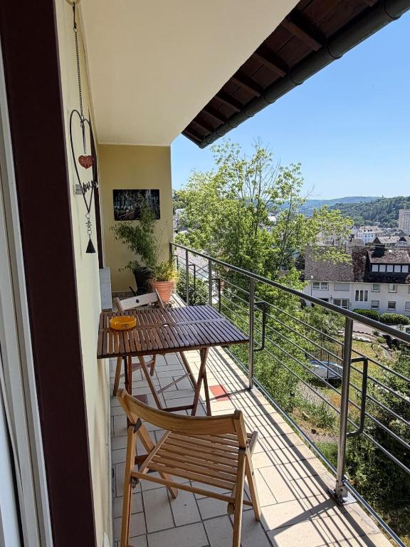 a balcony with a wooden table and a chair at Schöne Aussicht in Idar-Oberstein
