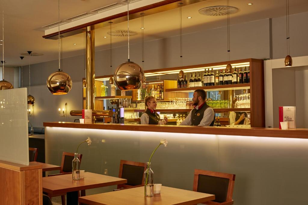 a man and a woman standing at a bar at H4 Hotel Kassel City, Trademark Collection by Wyndham in Kassel