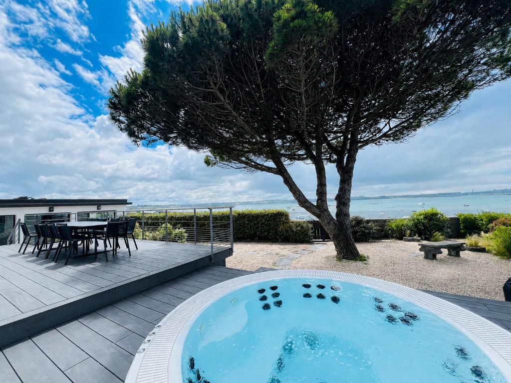 a hot tub on a patio with a table and a tree at Villa les dunes in Carantec