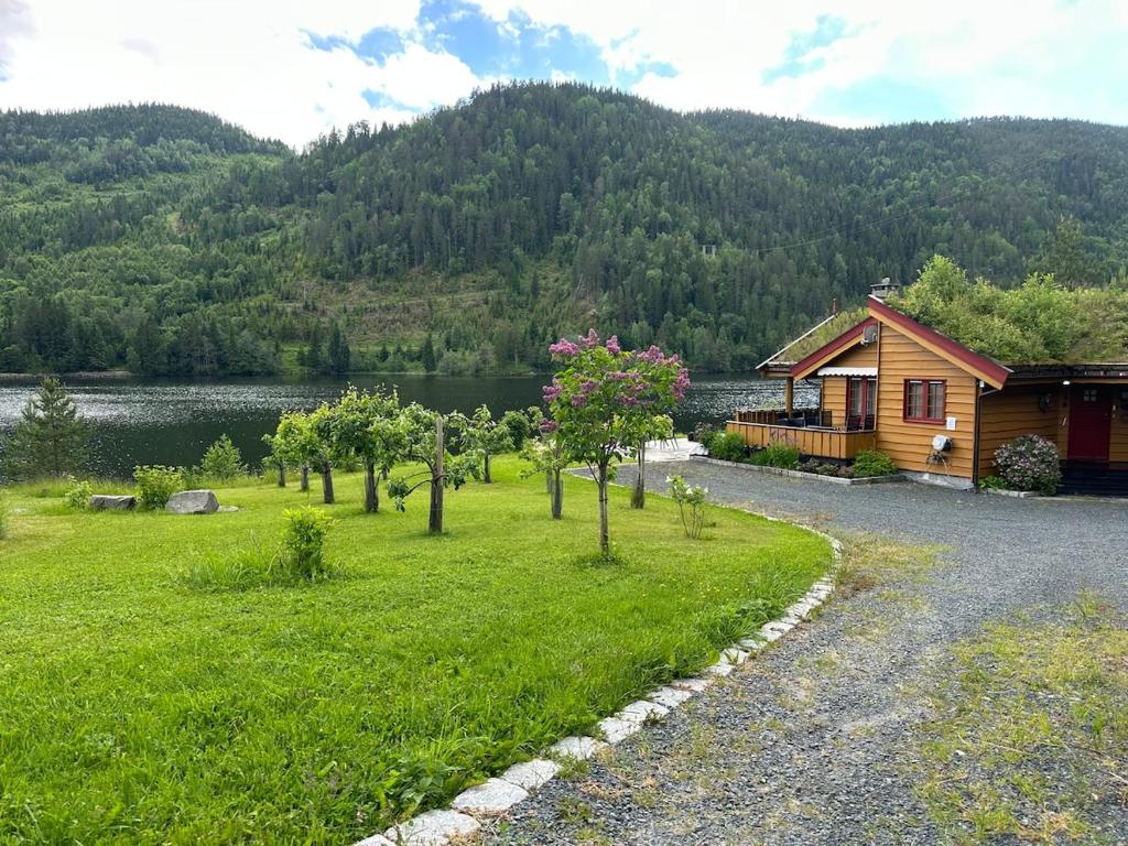 a cabin with a grassy yard next to a lake at Lakefront Cabin on Vråvatn in Kviteseid