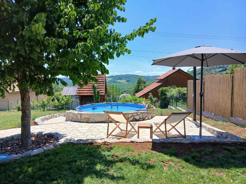 a patio with two chairs and an umbrella and a pool at Brvnara Nenadić in Užice