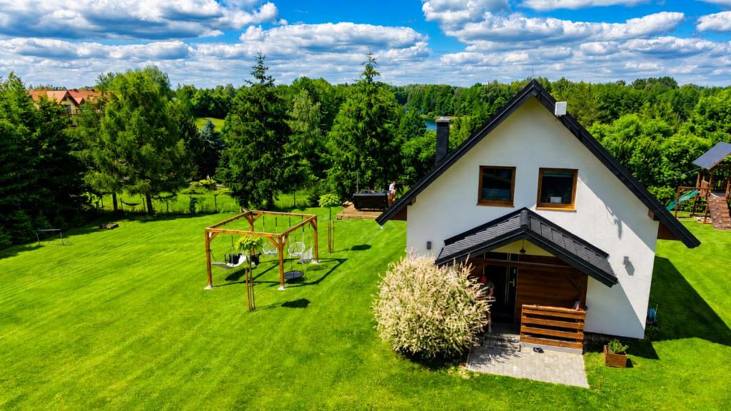 an aerial view of a house on a green field at Domek z kominkiem nad jeziorem z jacuzzi ogrodowym in Sumowo