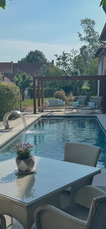 a swimming pool with a table and chairs next to it at B&B De Rentmeesterhoeve in Reningelst