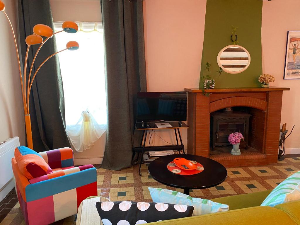 a living room with a fireplace and a tv at Rêve du Revert in Roz-sur-Couesnon