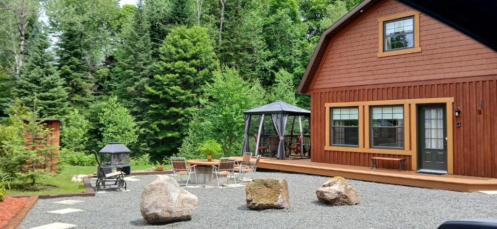 a cabin with a table and a gazebo and some rocks at Le Iris in Saint-Alexis-des-Monts
