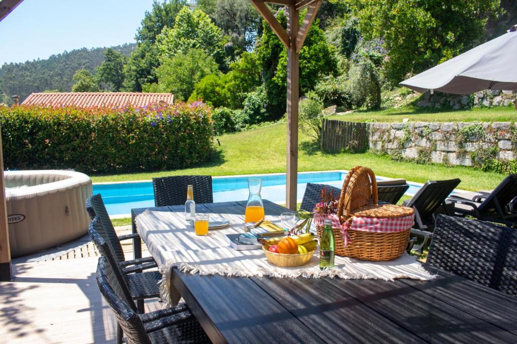 a picnic table with a basket of fruit and wine at Casa da Pontelha by Gerês Casas in Terras de Bouro
