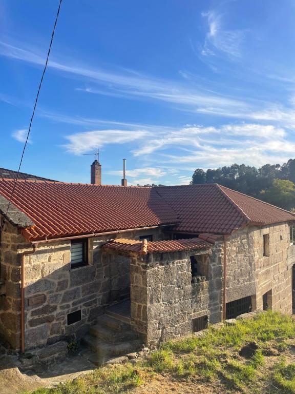 an old stone house with a red roof at As Fontaiñas in Beiro