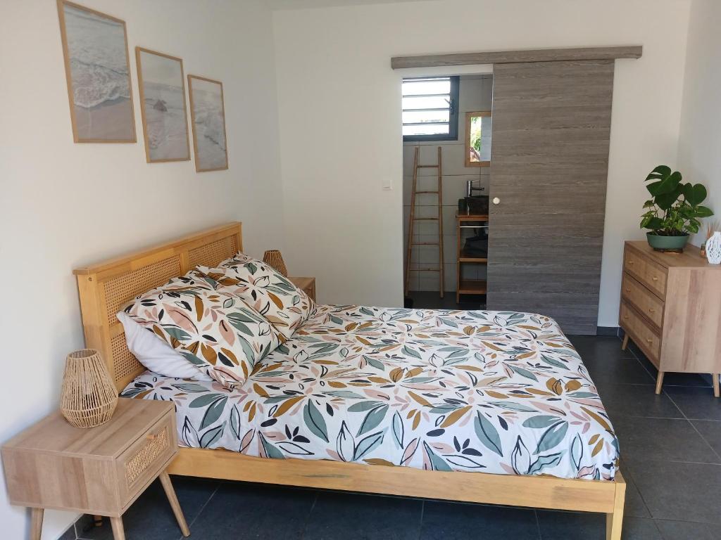a bedroom with a bed with a comforter and a table at Chez Sab et chaton in Saint-Leu