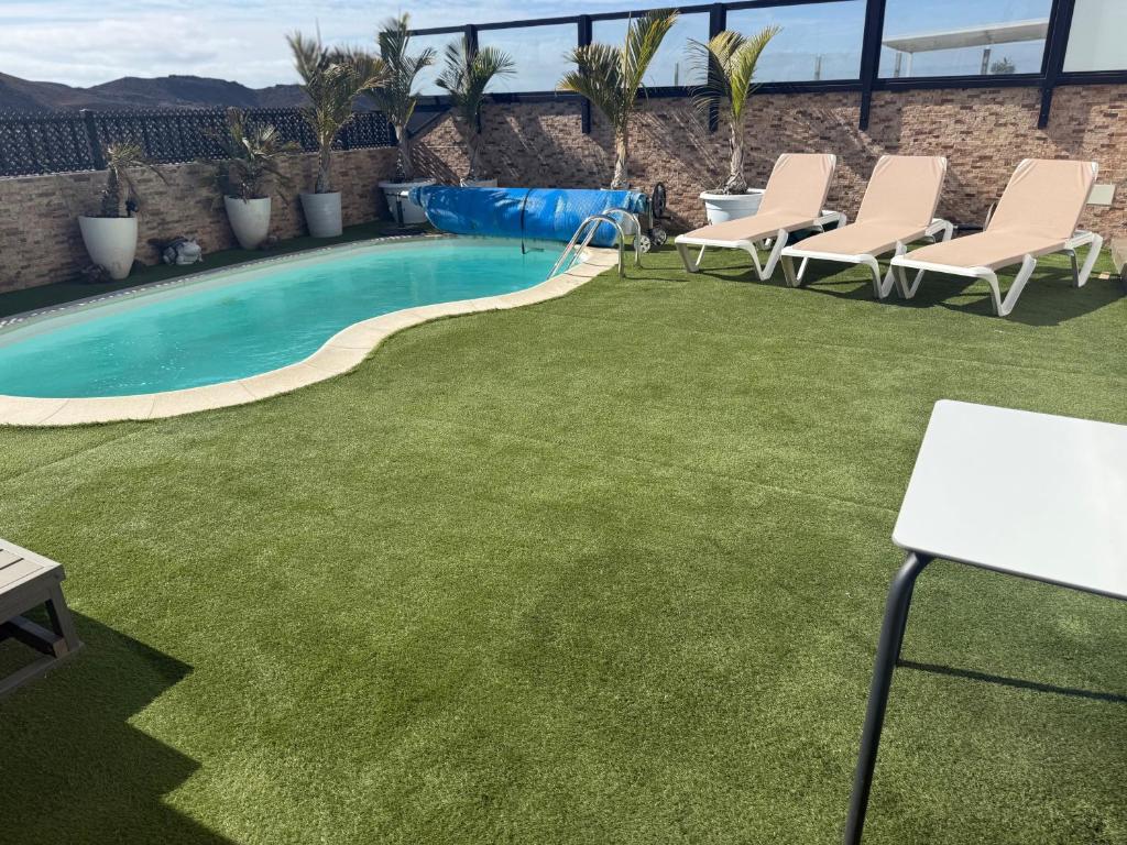 a lawn with chairs and a swimming pool at Corralejo Branded Residensed in Corralejo