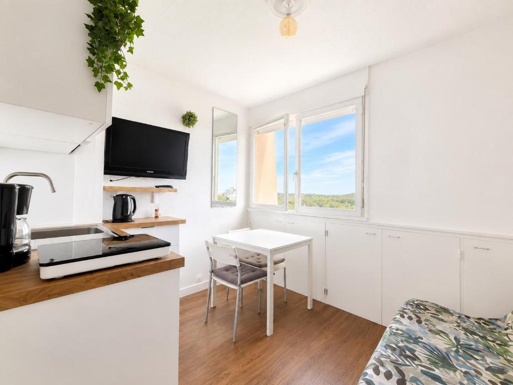 a small white kitchen with a table and a chair at Studio - Marina 4 - 17 allée des Pinons - 5-1 in Saint-Jean-de-Monts