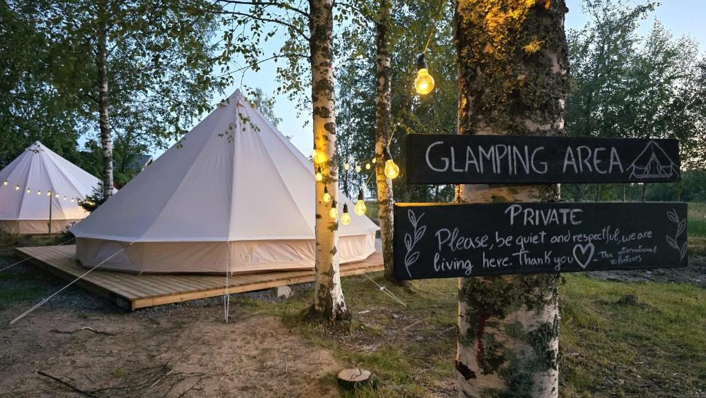 a white tent with a sign next to a tree at Glamping by the sea in Äggrund