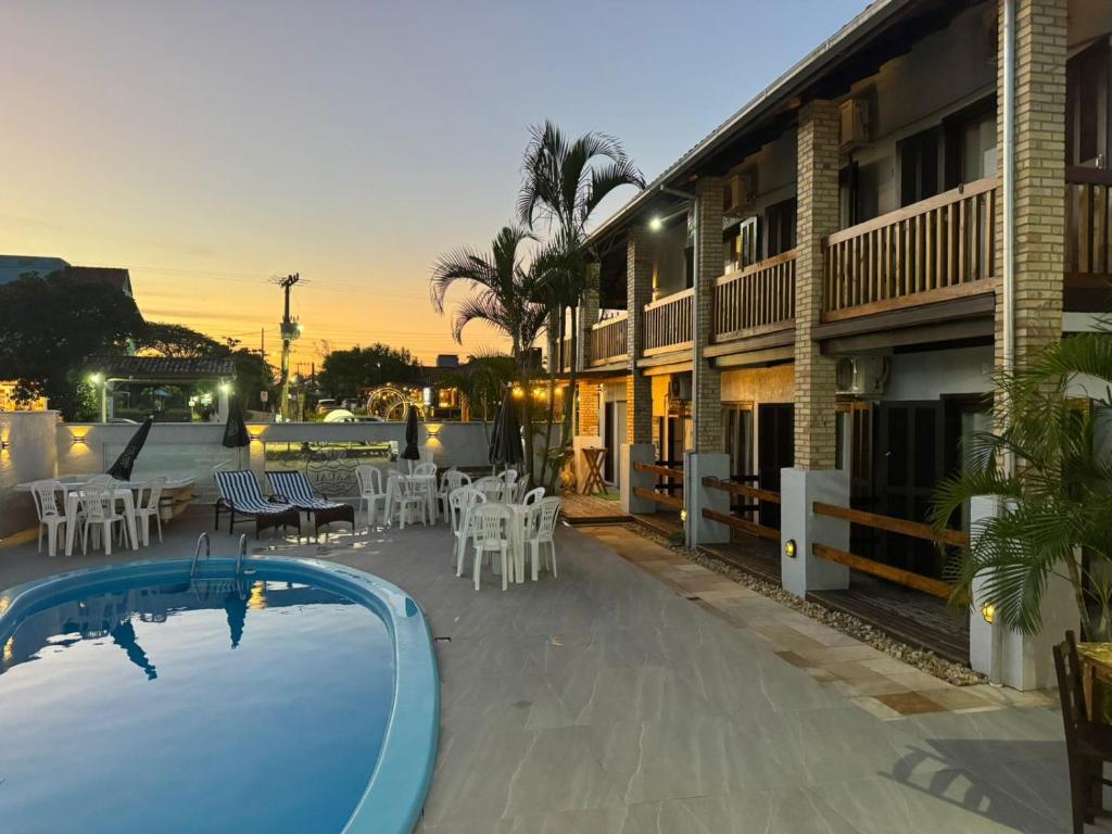a resort with a pool and tables and chairs at Pousada Kauai in Praia do Rosa