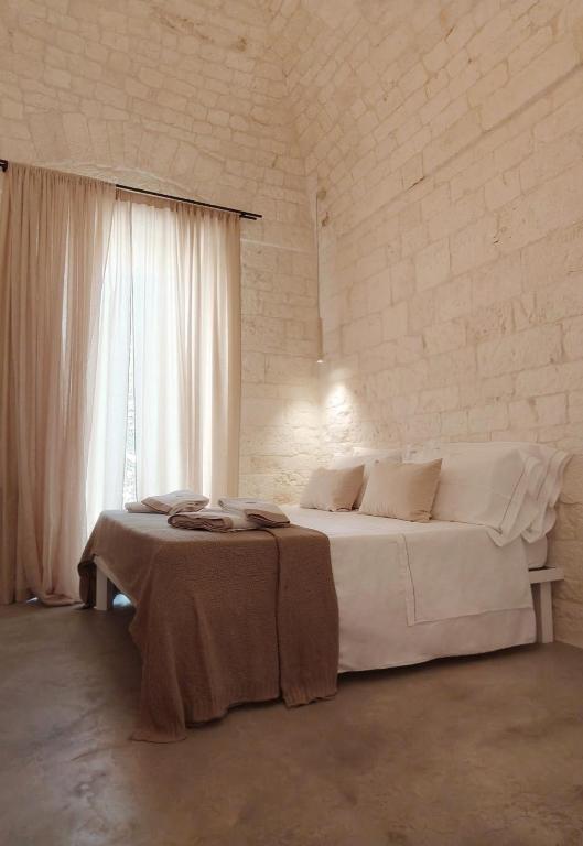a white bedroom with a large bed and a window at Palazzo Marconi in Locorotondo