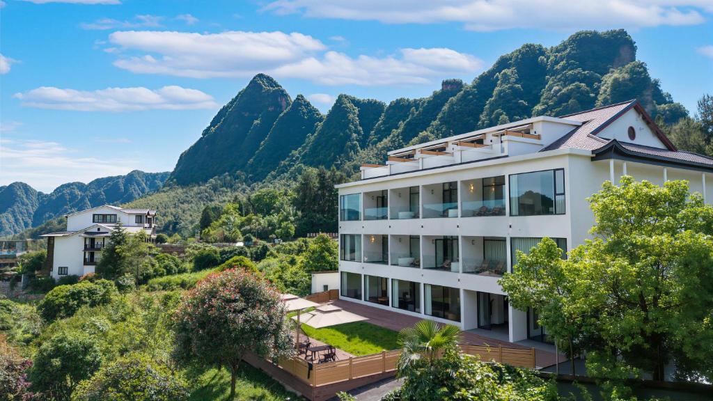 a building with mountains in the background at Zhangjiajie National Park Nvue Resort Free Laundry & Dry Service,Free Fresh coffee& Customizing Tour Plan in Zhangjiajie