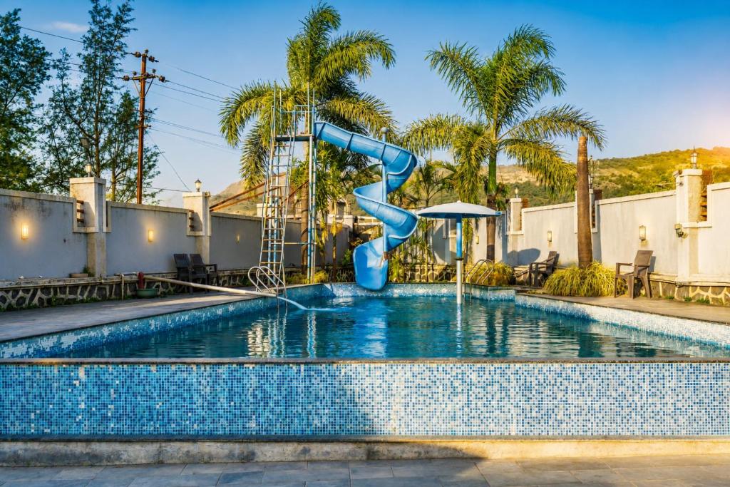 a blue water slide in a swimming pool at Royal Heritage Lonavla - 7BHK with Turf in Lonavala