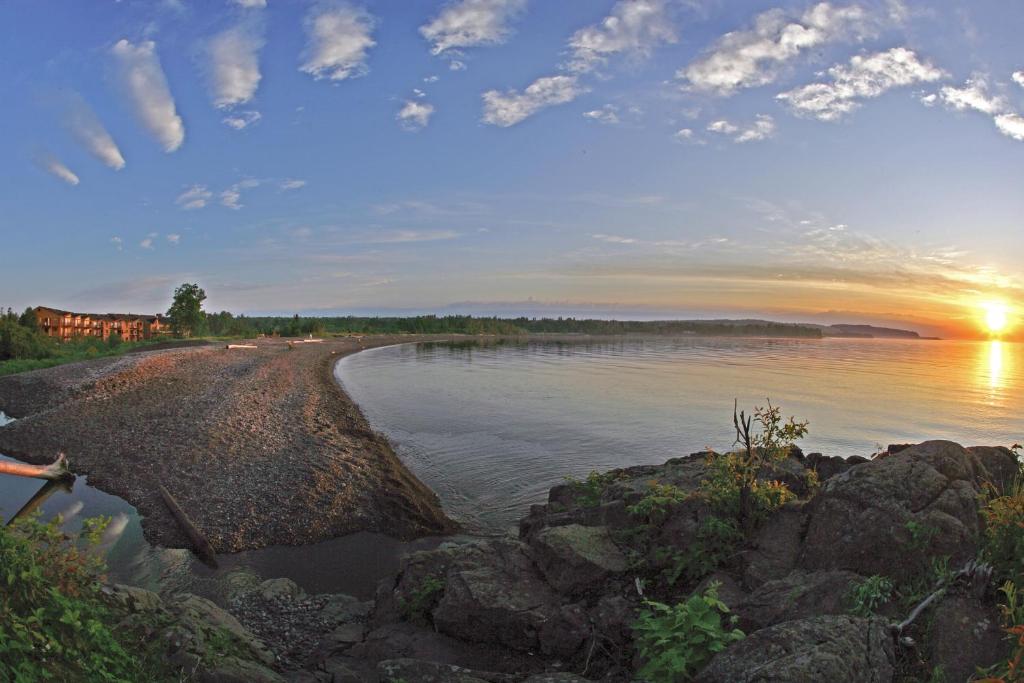 a sunset on the shore of a body of water at Superior Shores Resort in Two Harbors