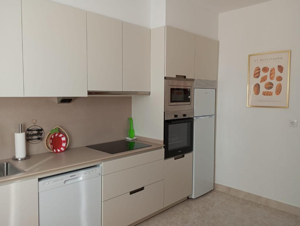 a kitchen with white cabinets and a stove top oven at Apartamento A Canteira in O Grove