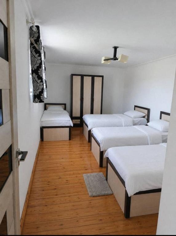 a room with four beds in a room with wood floors at Sho Hostel in Khorugh