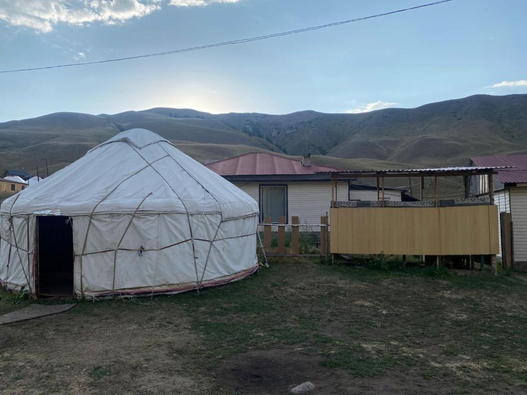 a tent in a yard with mountains in the background at Guest house Aibek in Kurmenty