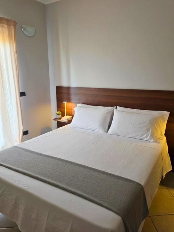 a bedroom with a large white bed with a wooden headboard at EffeVi - Bed and Books in Piaggine