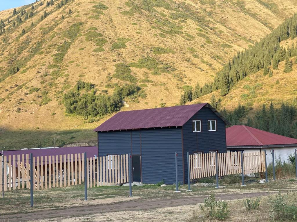 a blue barn with a fence in front of a mountain at Guest hous Aibek in Kurmenty