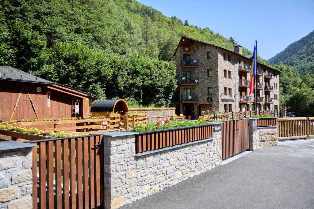 a resort with a stone fence and a building at Apartaments La Neu-Mountain Lodges & Restaurant in Ordino