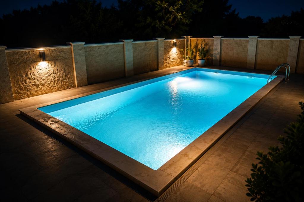 a swimming pool with lights in a backyard at night at Villa Zlatan Poolside in Bosanska Gradiška
