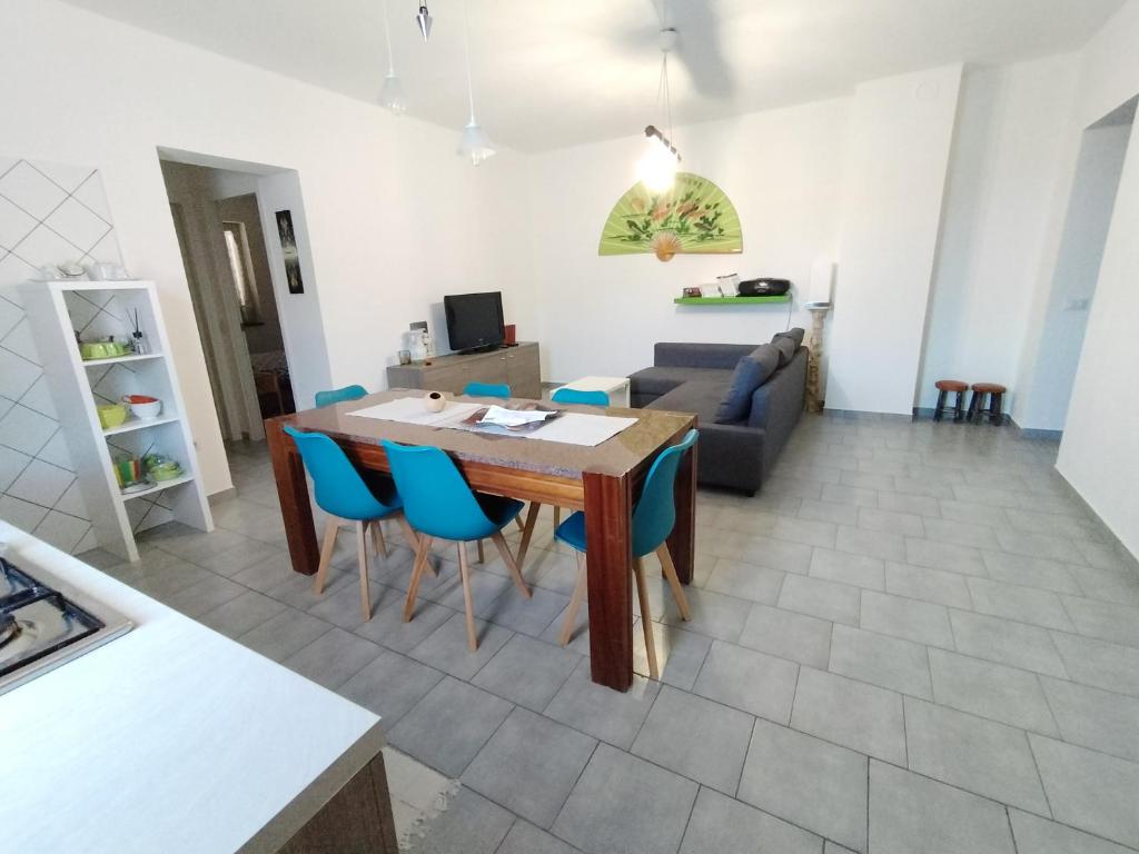 a kitchen and living room with a wooden table and blue chairs at La vedetta di Castrocucco in Tortora