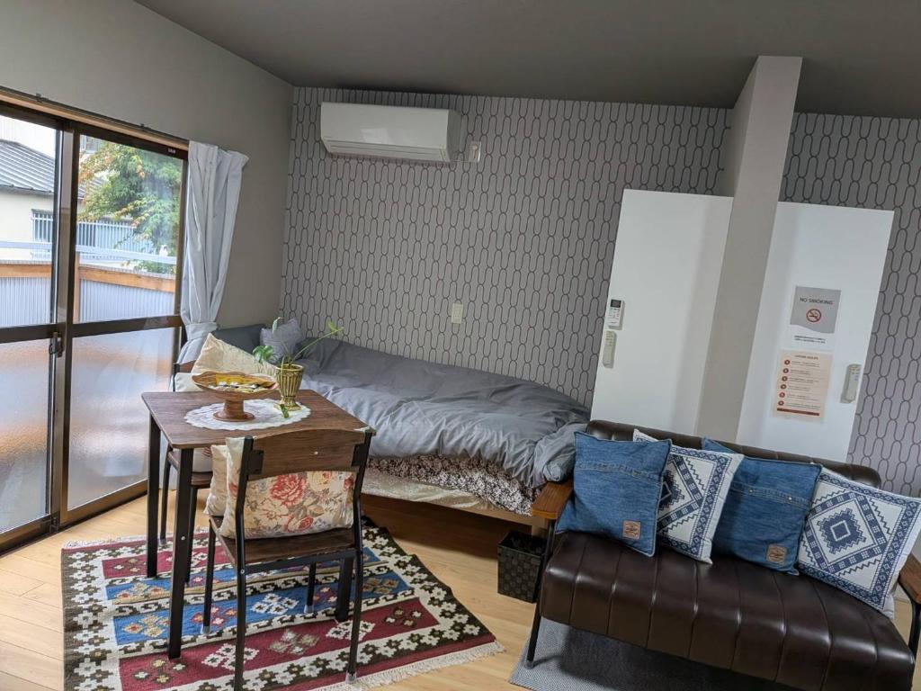 a room with a bed and a table and a couch at Kumanokodo KURA in Shingū