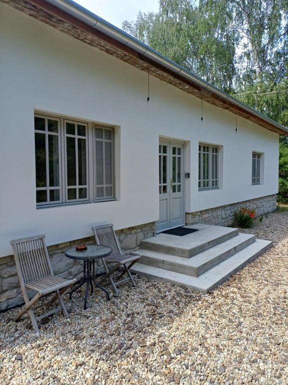 a white house with two chairs and a table at Füveskert in Erdőbénye