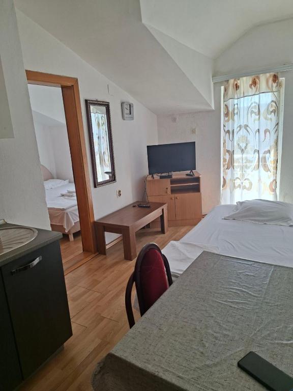 a bedroom with a bed and a desk and a television at Apartmani Lazić No 9 in Gracanica
