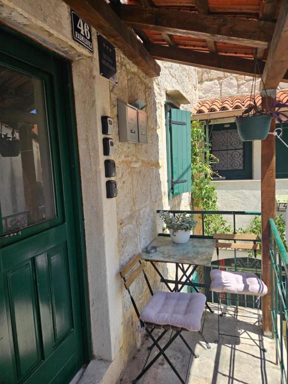 a table and chairs on a porch with a green door at Kruna apartments est 2024 in Split