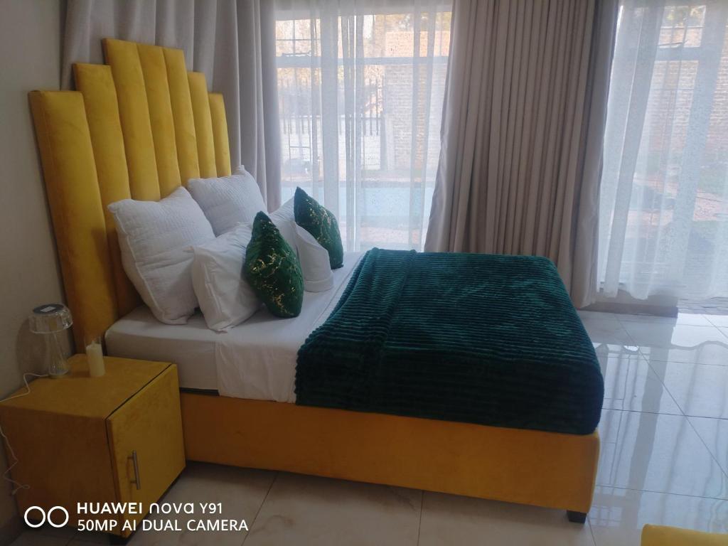 a bedroom with a bed with a yellow headboard and pillows at The Hush House in Roodepoort