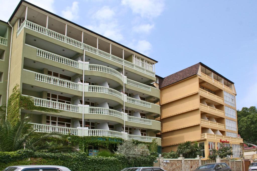 an apartment building with balconies next to a parking lot at Paradise Hotel in Adler