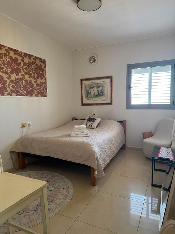 a small bedroom with a bed and a chair at apartments with separate kitchen by the sea in Ashdod