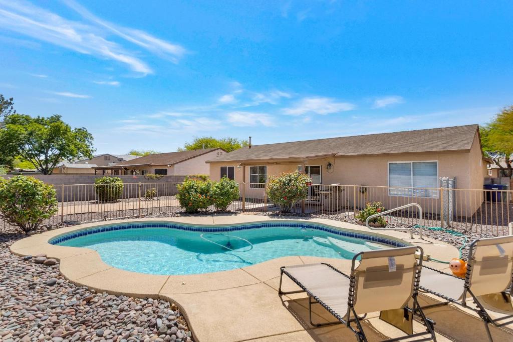 a swimming pool with two chairs and a house at Peaceful Valley in Tucson