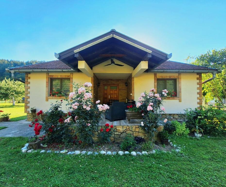 a yellow house with flowers in front of it at Kuća za odmor "Mira" in Foča